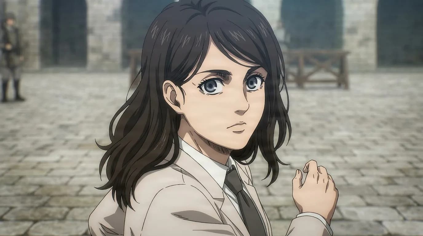 Cart Titan holder Pieck Finger looking back over her shoulder in a stone courtyard, long dark hair, pale jacket, shirt and tie.