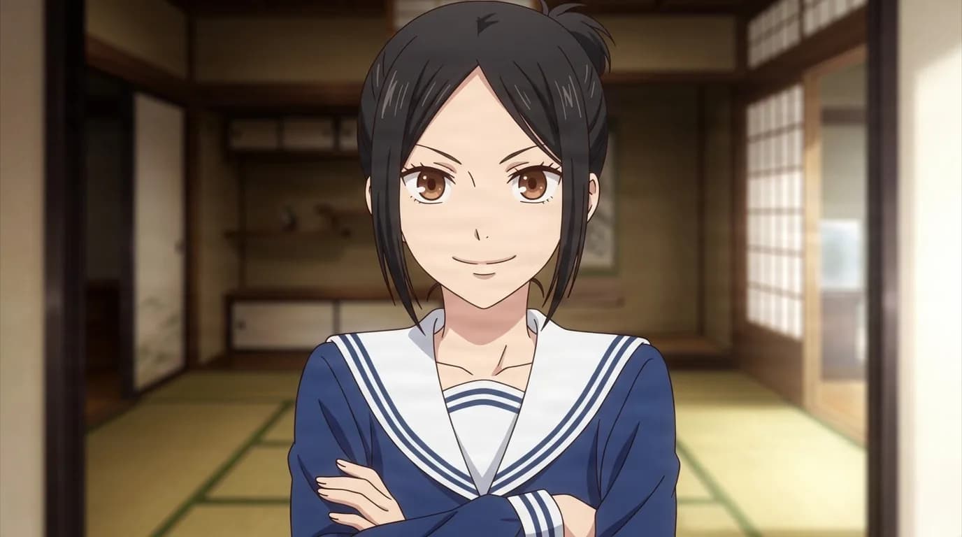 Michi Manabe with black hair tied in a small bun, arms folded over a navy sailor uniform, smiling in a traditional tatami room