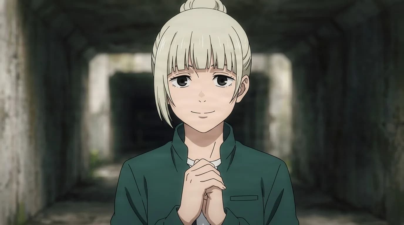 Aki Sasada, a pale blonde girl with her hair in a bun, smiling with hands clasped in a dim concrete corridor