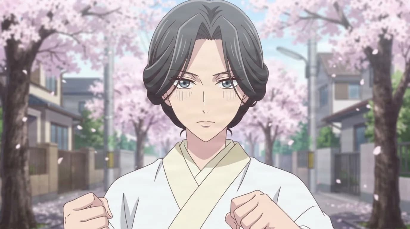 Okami Sohma, a woman with dark wavy hair in a white and cream kimono, both fists raised in front of her on a street of blossoming cherry trees